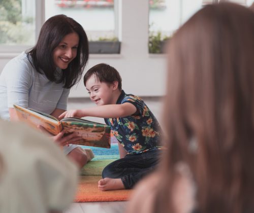 Reading time in an elementary school or kindergarten, a teacher reads a book to children in an elementary school or kindergarten. The concept of pre-school education. Selective focus.